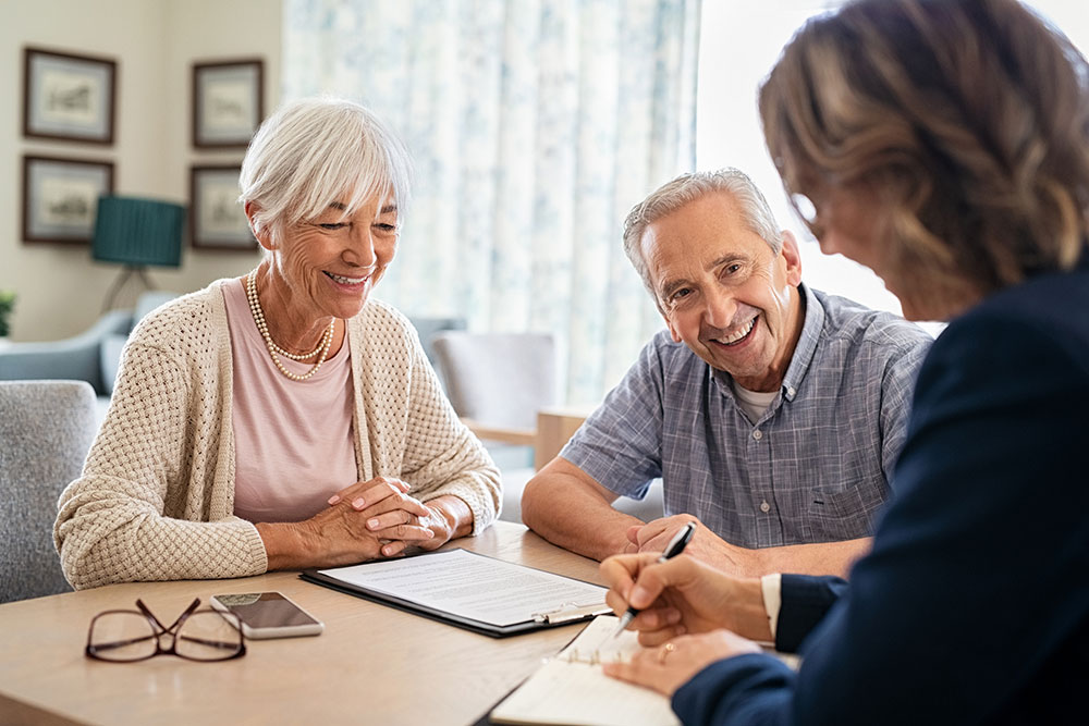 Couple speaks with financial advisor at desk.