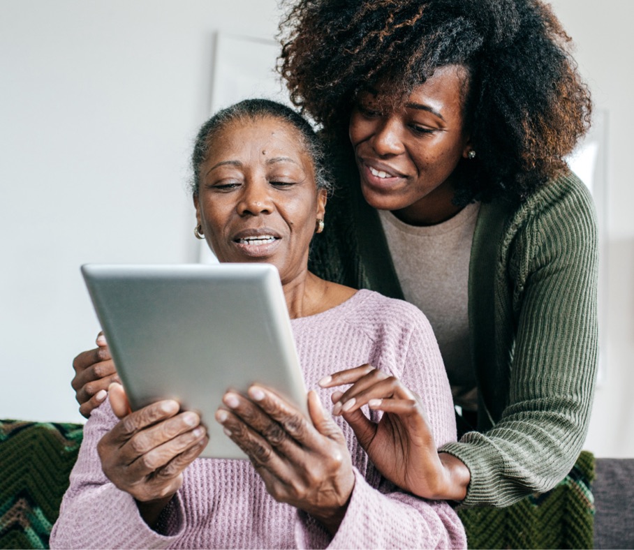 Woman helps senior navigating tablet.