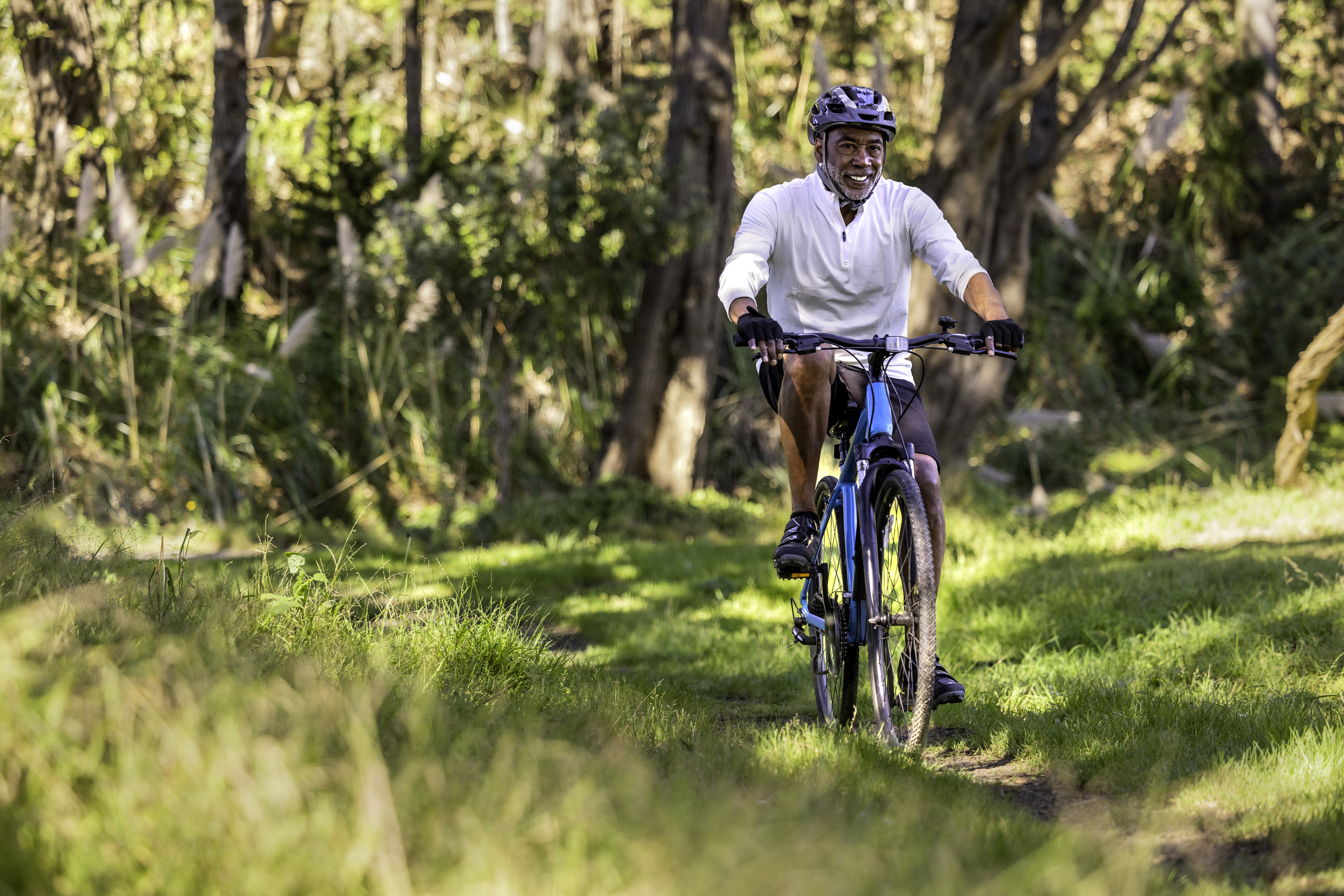 Senior man biking down wooded path