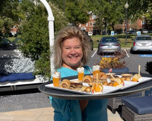 Ginger Cove employee serving platter of food outdoors